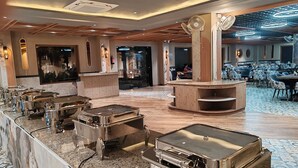 Een ruime lobby met een bar in het midden, zitgedeeltes en een decoratief plafond.