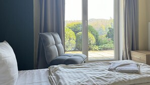 Une chambre d’hôtel avec un lit, une chaise et une grande fenêtre avec des rideaux.