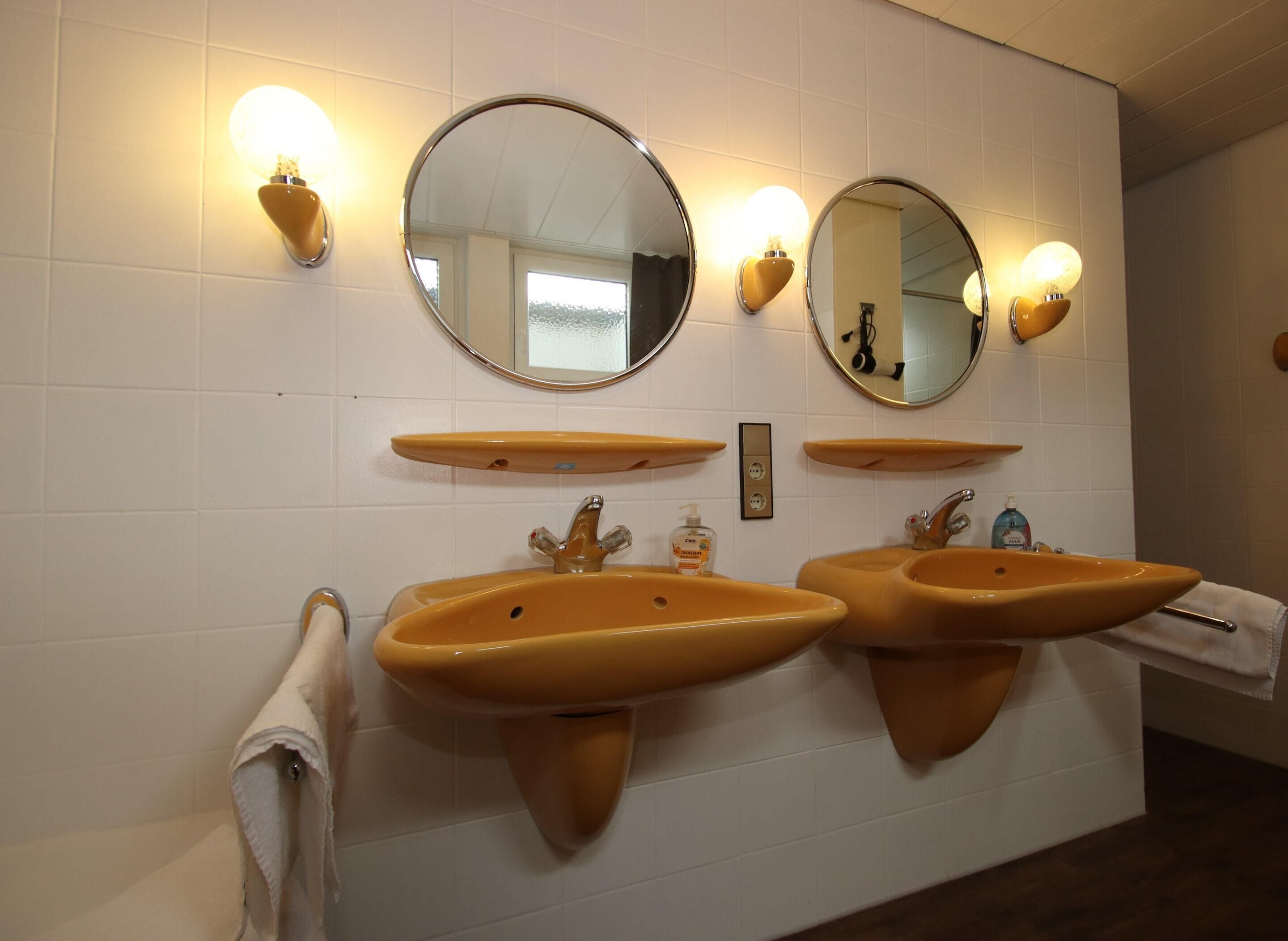 Un baño con dos lavamanos, dos espejos adosados a la pared y dos luminarias empotradas.