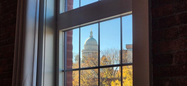A window with a view of a building with a dome, likely a capitol, through a grid pattern.