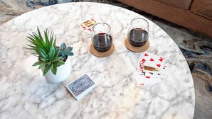 Un tavolo in marmo con due bicchieri di vino rosso, una pianta in vaso e carte da gioco.