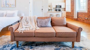 Un soggiorno moderno con un divano marrone, una coperta decorata e un tappeto blu e bianco.