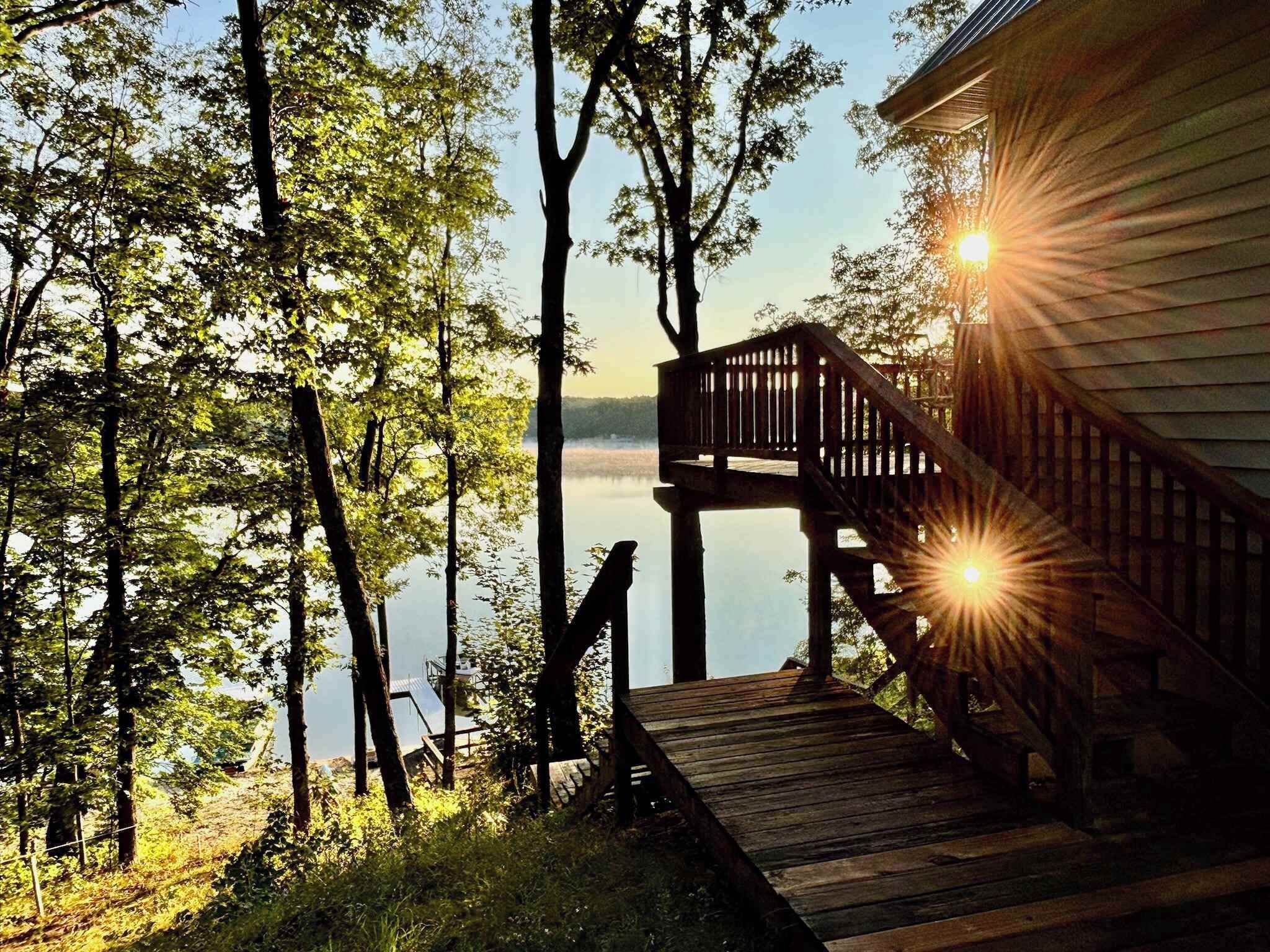Una terraza de madera que conduce a una cabaña con vista a un lago y árboles.