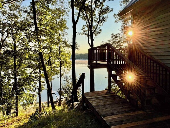 A wooden deck leading to a cabin with a view of a lake and trees. - Soaking Spot on Sand Lake, Irons (Irons)