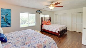 Quarto com cama, ventoinha no teto, janela e porta.