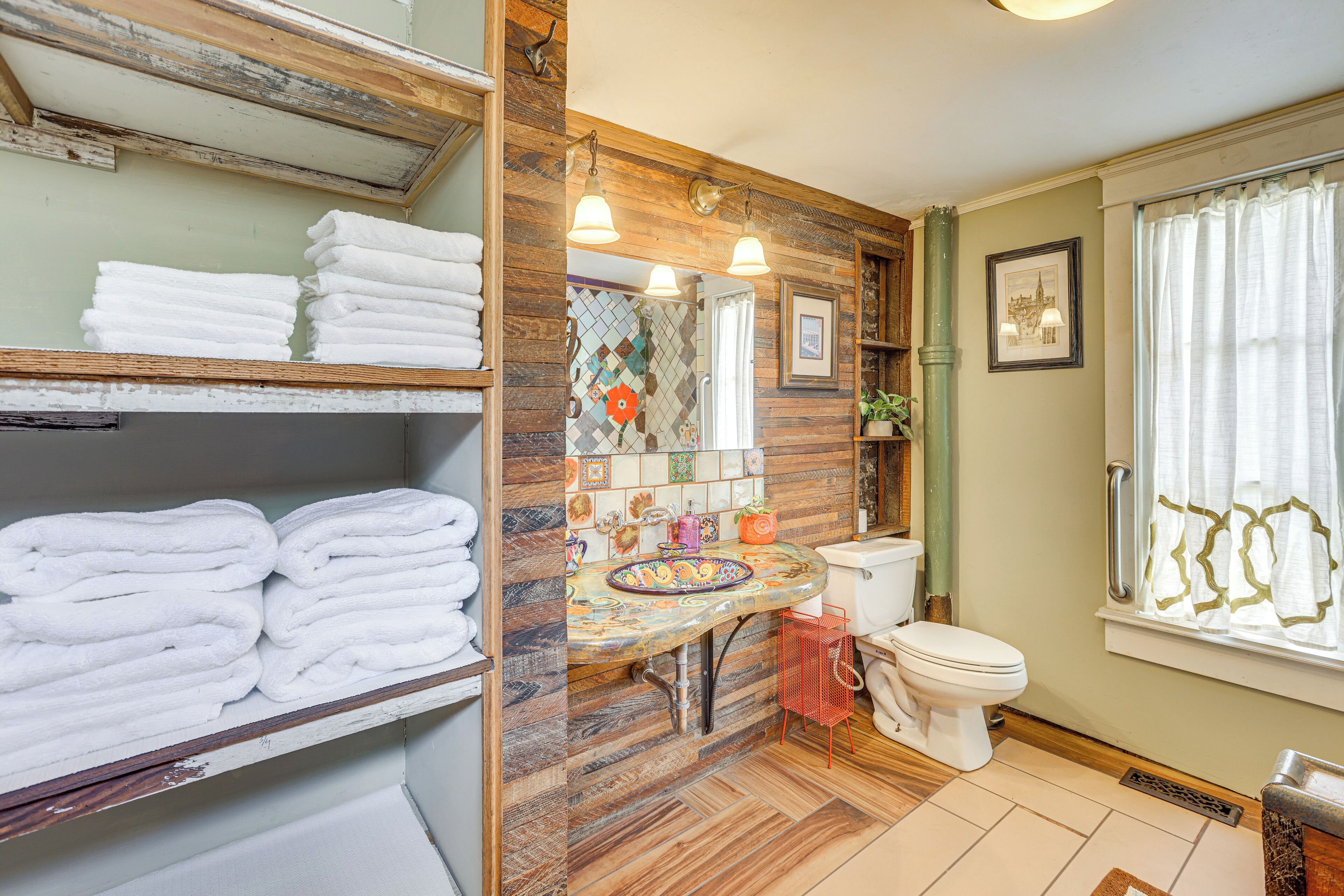 A bathroom with a wooden vanity, a toilet, and a sink with a decorative backsplash.