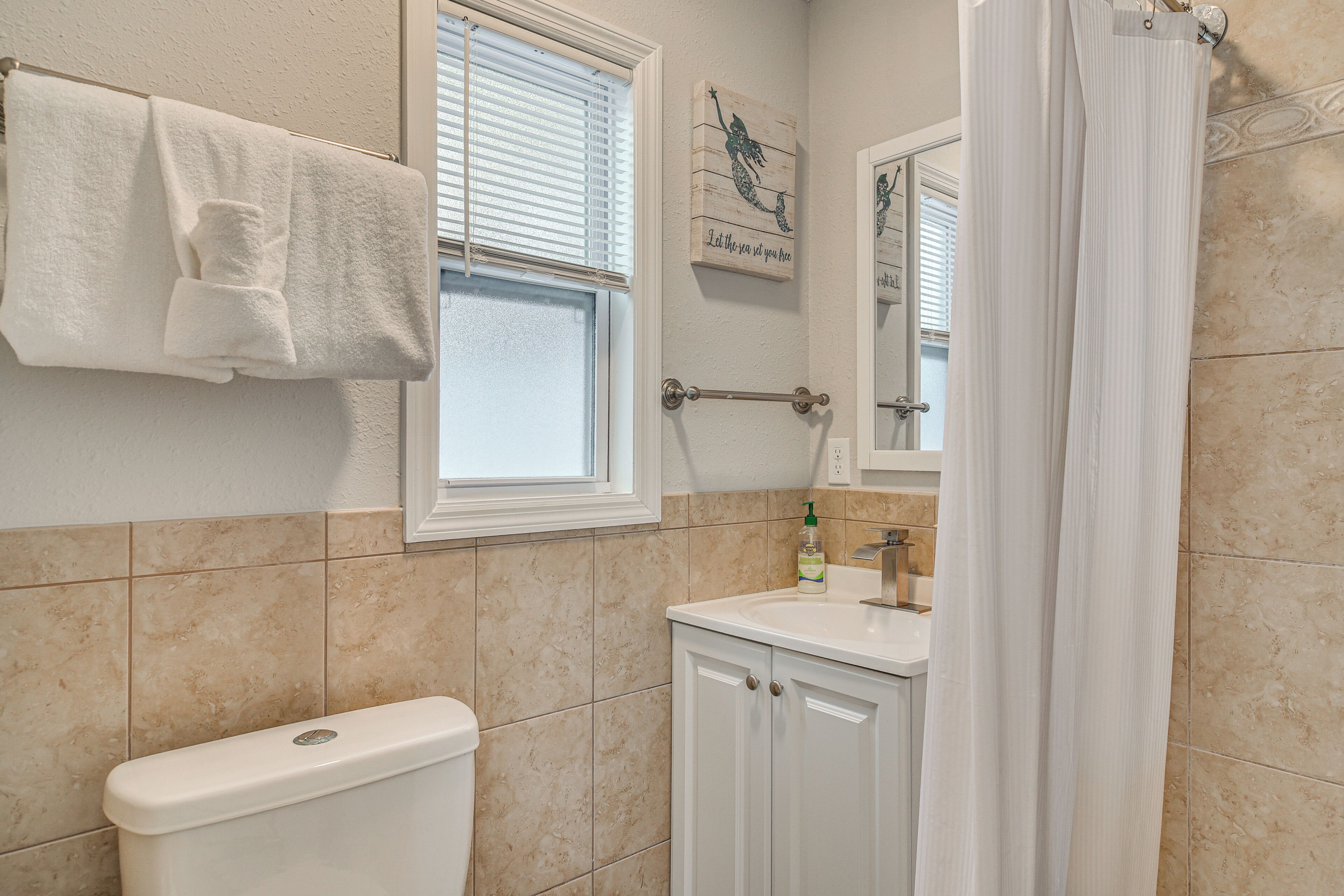 A bathroom with a toilet, sink, and window with blinds.