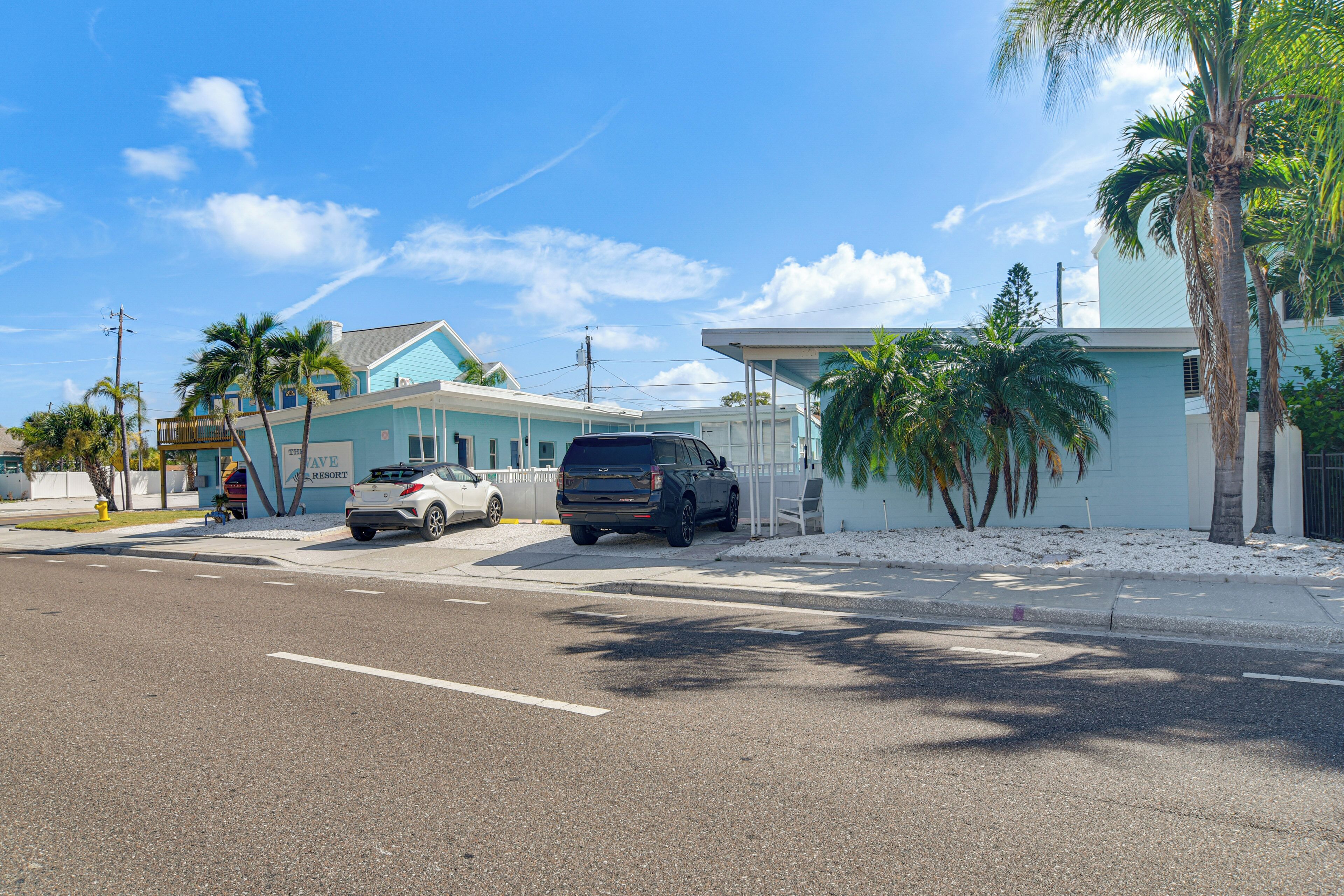 Vista de la calle con un edificio que dice 'TAYNE RESORT' y un SUV estacionado.