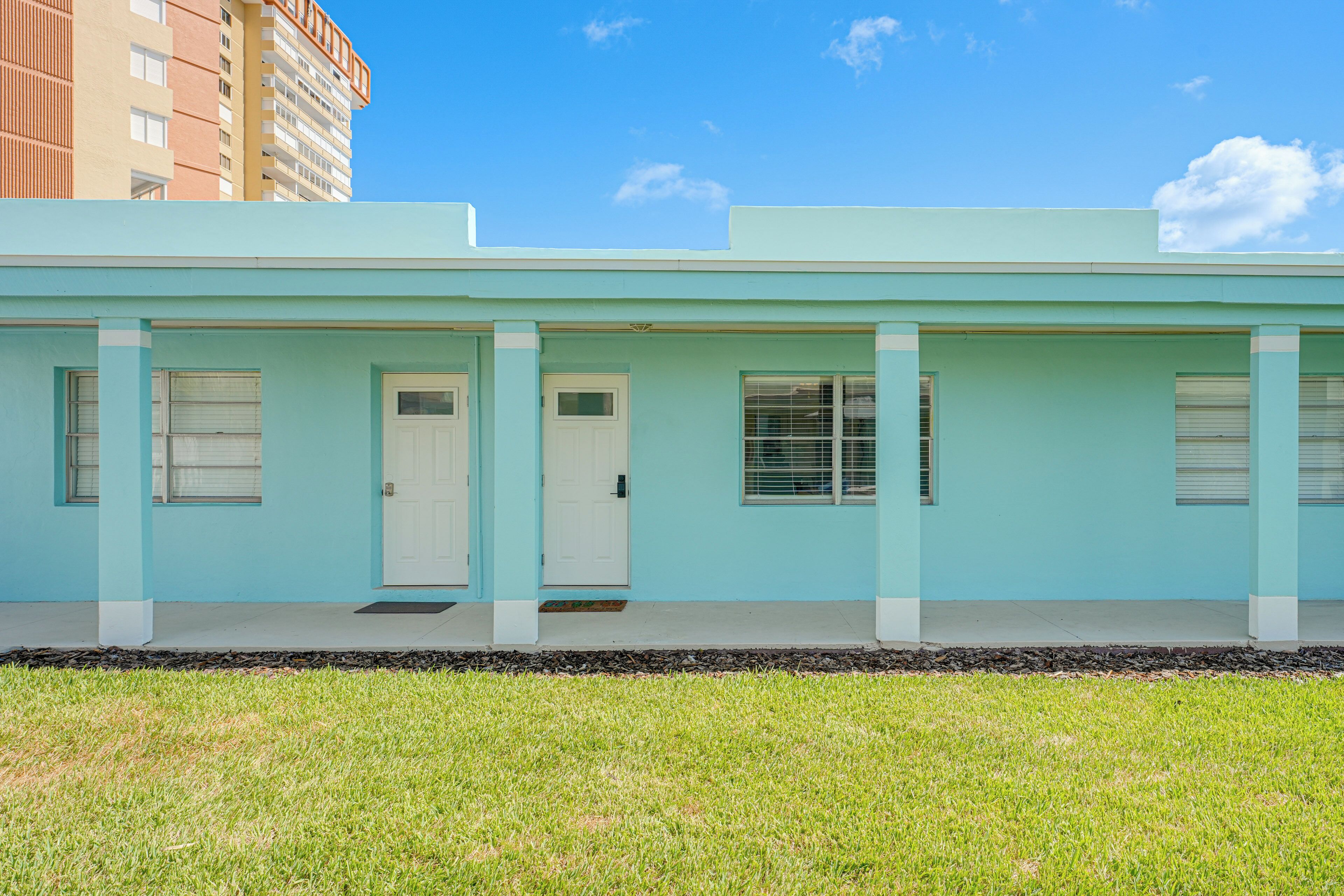 A light blue building with a flat roof, a front door, and windows.