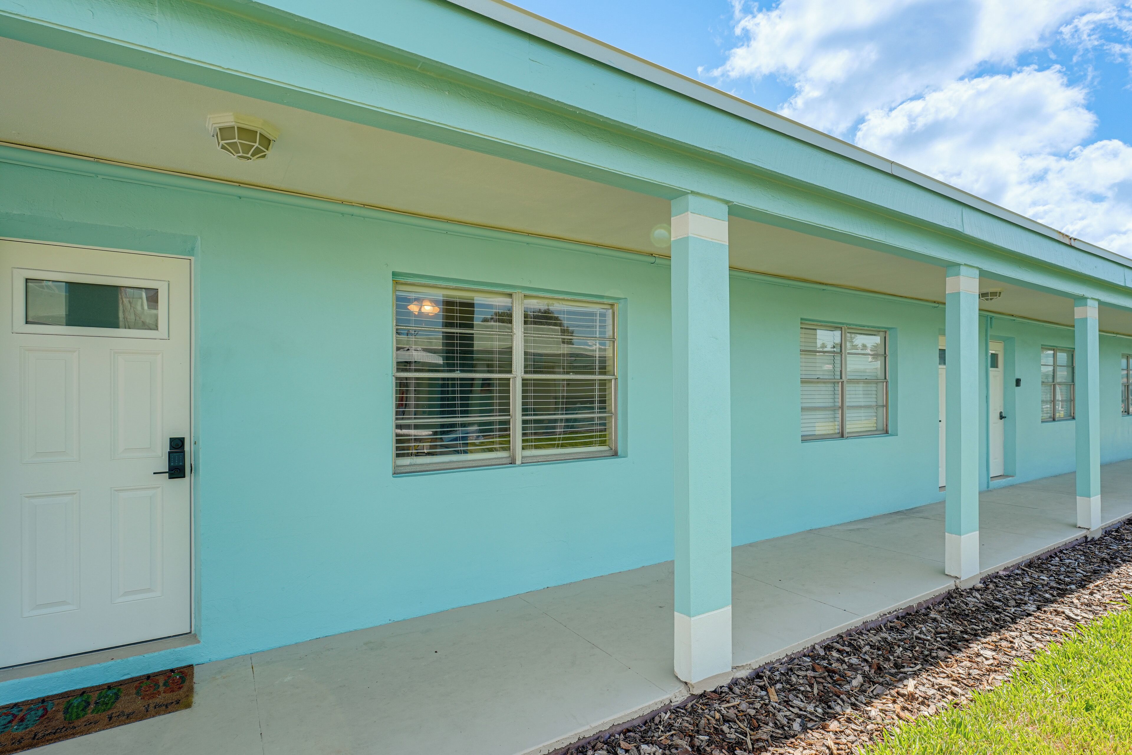 A building with a light blue exterior, white doors, and windows with blinds.