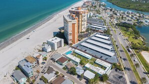An aerial view of a coastal city with a beach, a river, and a mix of residential and commercial buildings. - Beachfront Condo: Redington Shores Retreat! (Redington Shores)