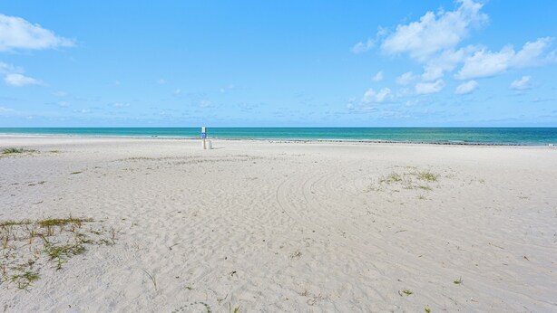 A wide sandy beach with a clear blue sky and ocean. - Beachfront Condo: Redington Shores Retreat! (Redington Shores)