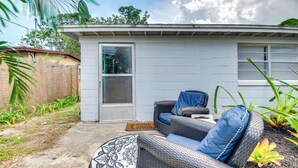 Un espace patio aménagé avec des meubles en osier, une porte et un petit jardin.