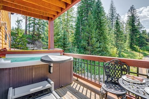 Una terraza de madera con un jacuzzi, asientos y una mesa con sillas.