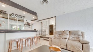 A modern living room with a sofa, a coffee table, and a kitchen area in the background. - Spacious Home - 6 Mi to Downtown Fresno! (Fresno)