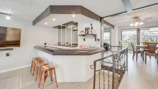 A modern kitchen with a bar area, wooden stools, and a dining table with chairs. - Spacious Home - 6 Mi to Downtown Fresno! (Fresno)