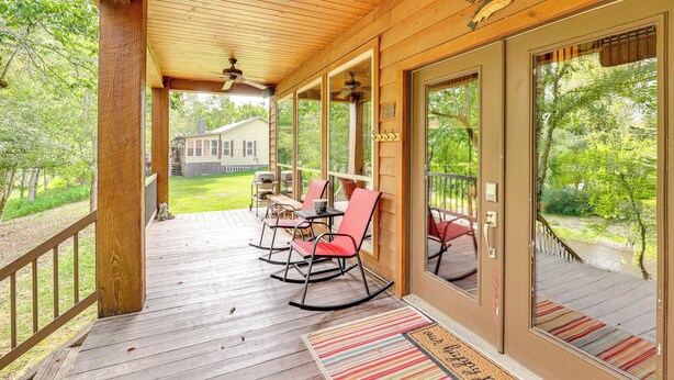 Eine überdachte Veranda mit Holzboden, Schaukelstühlen und einem Esstisch.