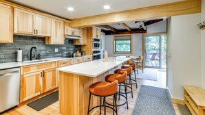 A modern kitchen with wooden cabinets, a large island with bar stools, and a view to a patio area.