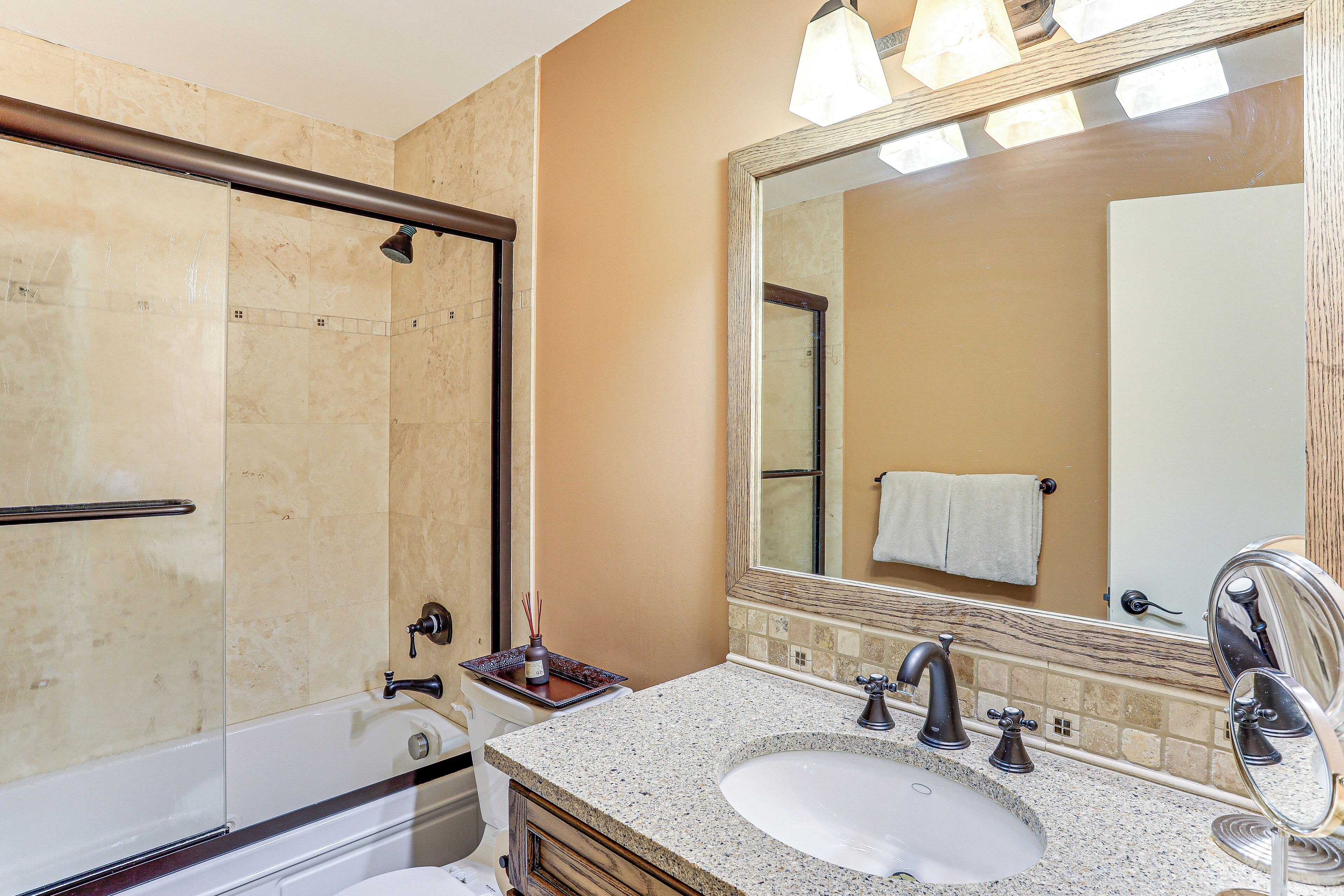 Un bagno con una vasca, un lavandino e un grande specchio.