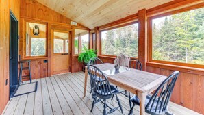 A wooden deck with a table and chairs, large windows, and a potted plant. - 'sunset House' Greensboro Forest Escape & Fire Pit (Stannard)