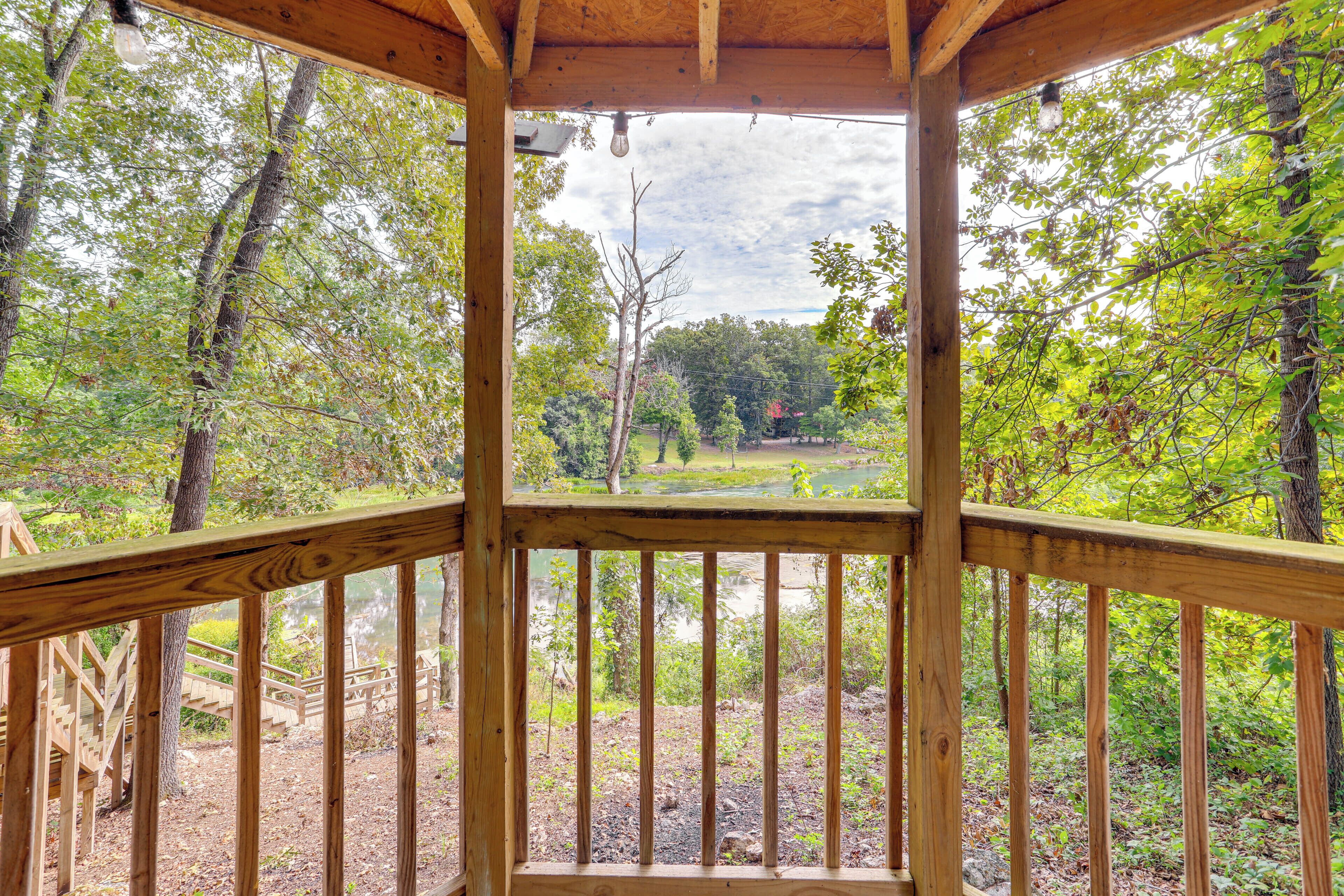 A wooden deck with a view of a forest and a lake.