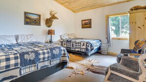 Un dormitorio con dos camas, un ventilador de techo y una cabeza de ciervo montada en la pared.