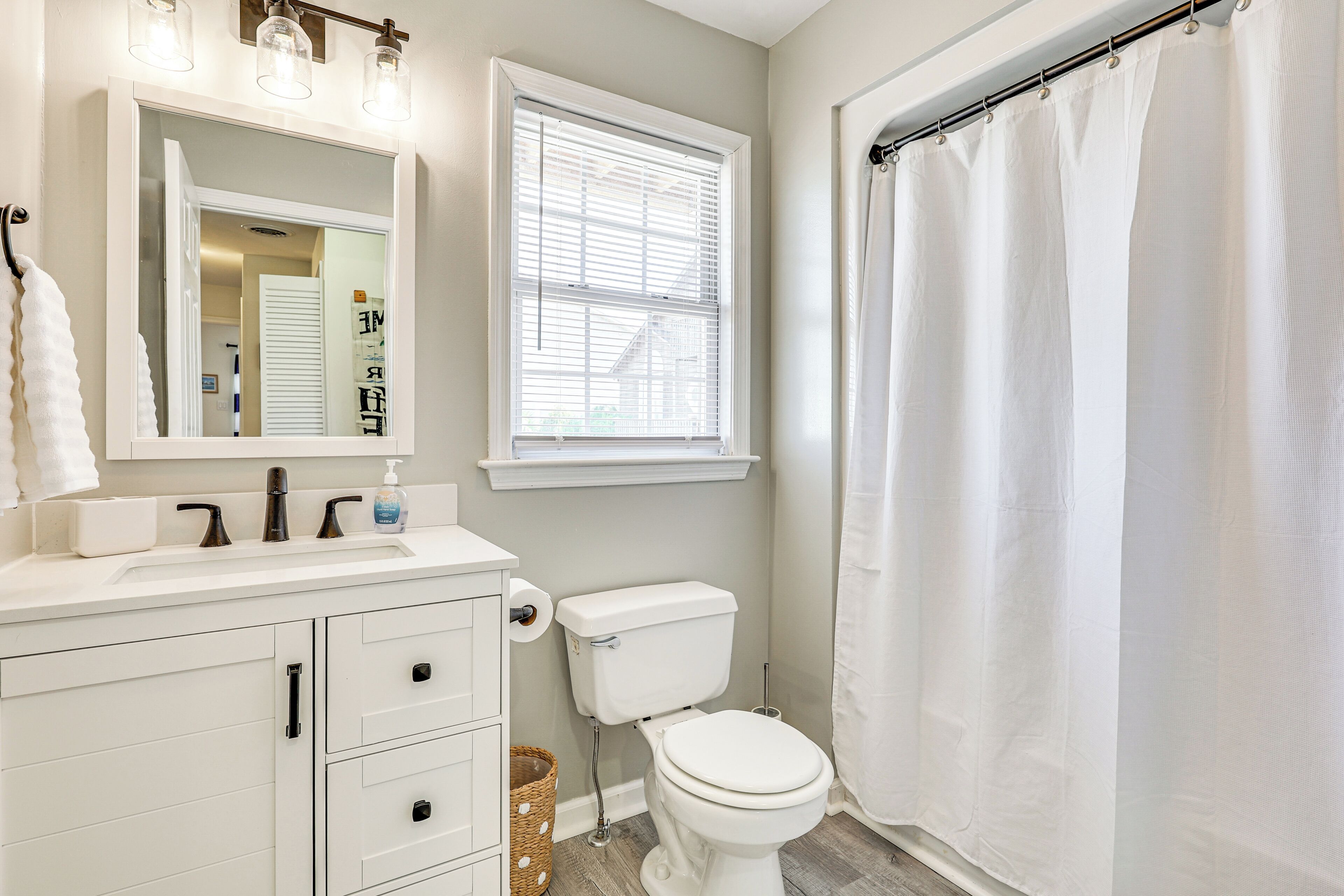 A bathroom with a white sink, mirror, and toilet.