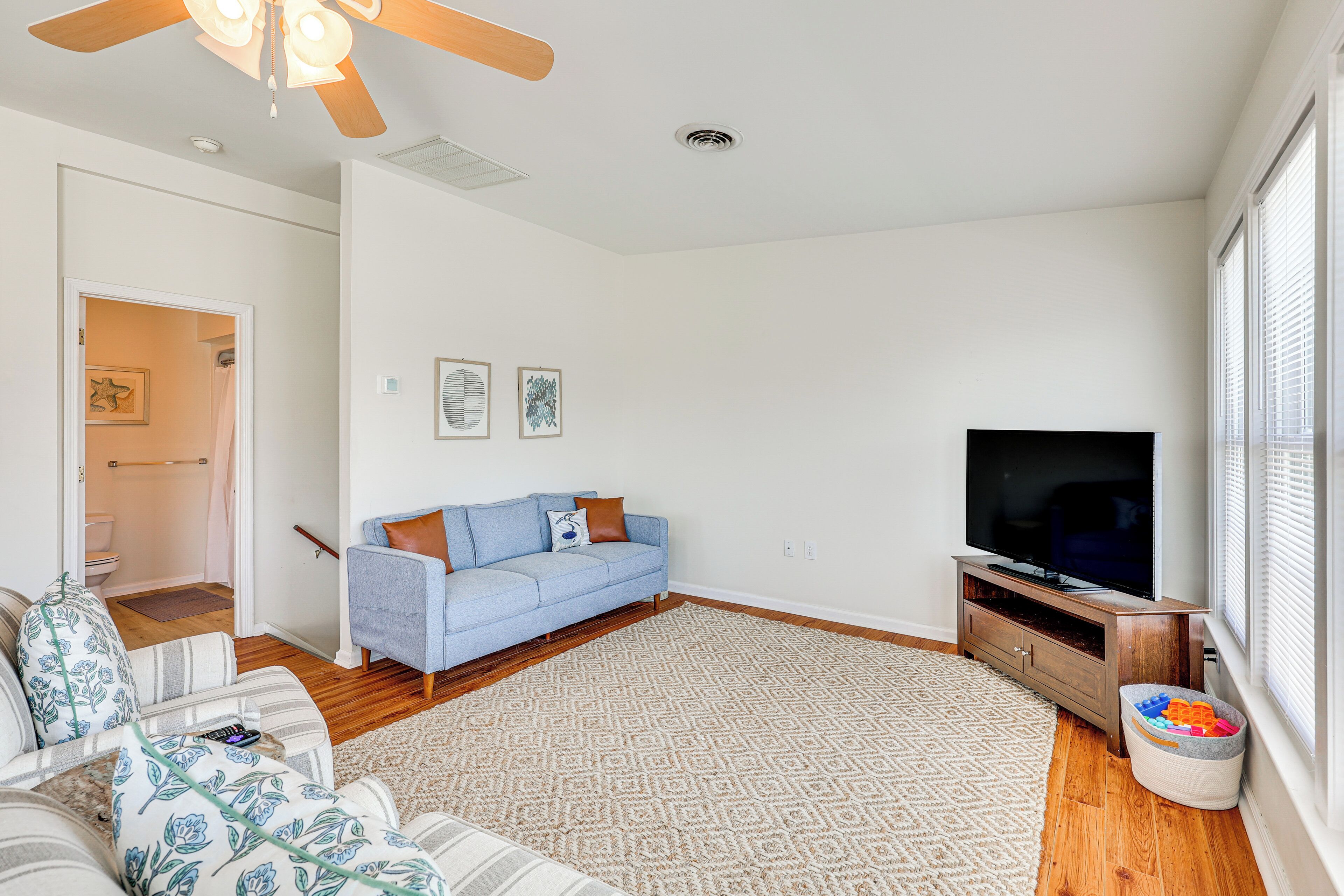 A living room with a blue sofa, a television, and a wooden floor.