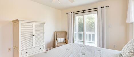 A bedroom with a large bed, a wardrobe, a chair, and a ceiling fan.