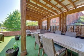 An outdoor patio with a wooden table and wicker chairs, surrounded by a brick wall and a view of a brick building. - Dtwn Lynchburg Apt w/ Shared Deck: Pets Welcome! (Lynchburg)