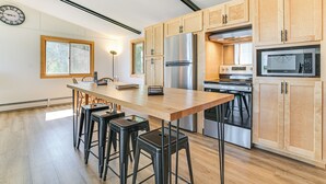 Una cocina moderna con armarios de madera, electrodomésticos de acero inoxidable y una isla central con taburetes de bar.
