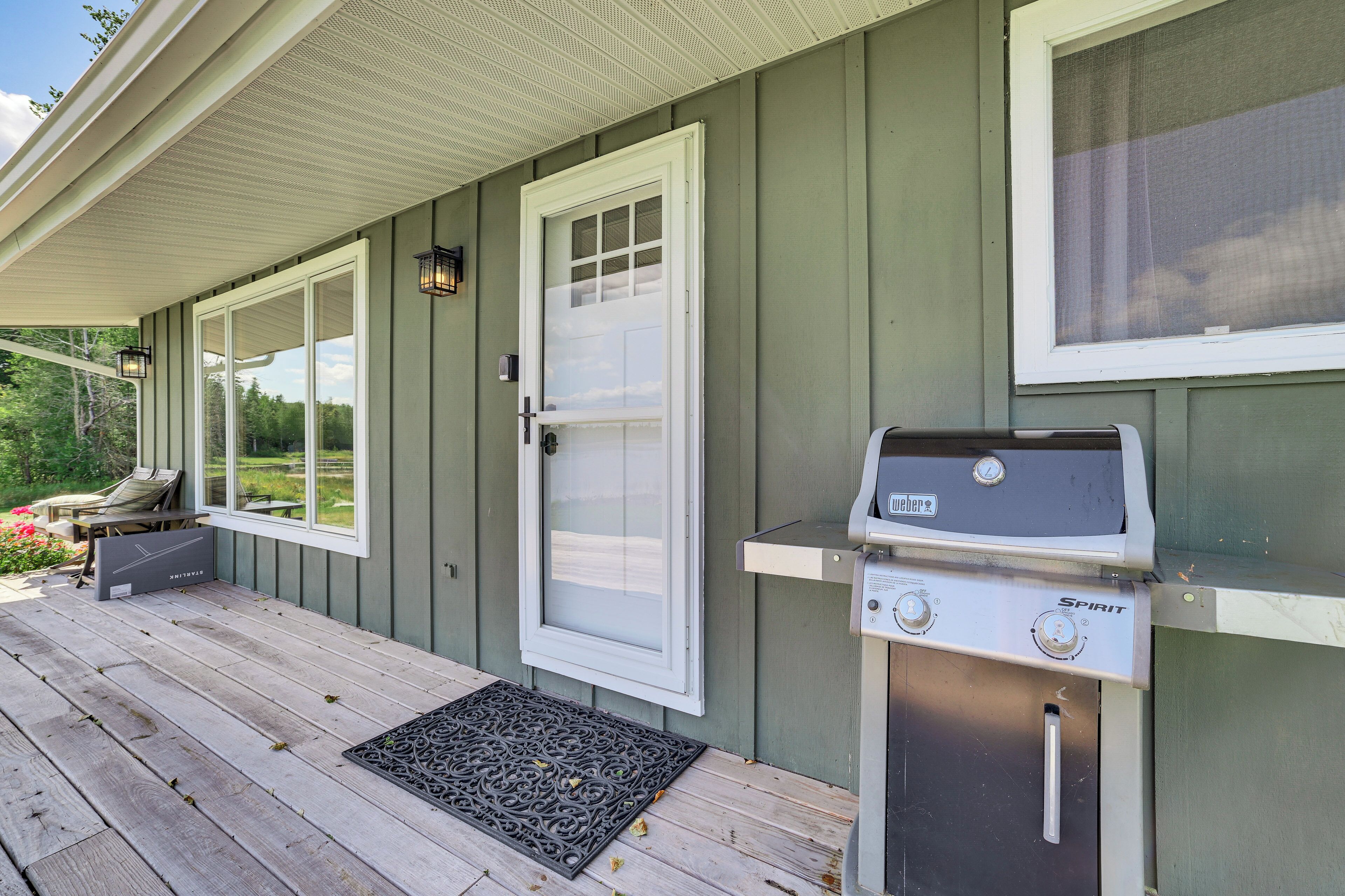 A covered porch with a grill, a door, and a window.