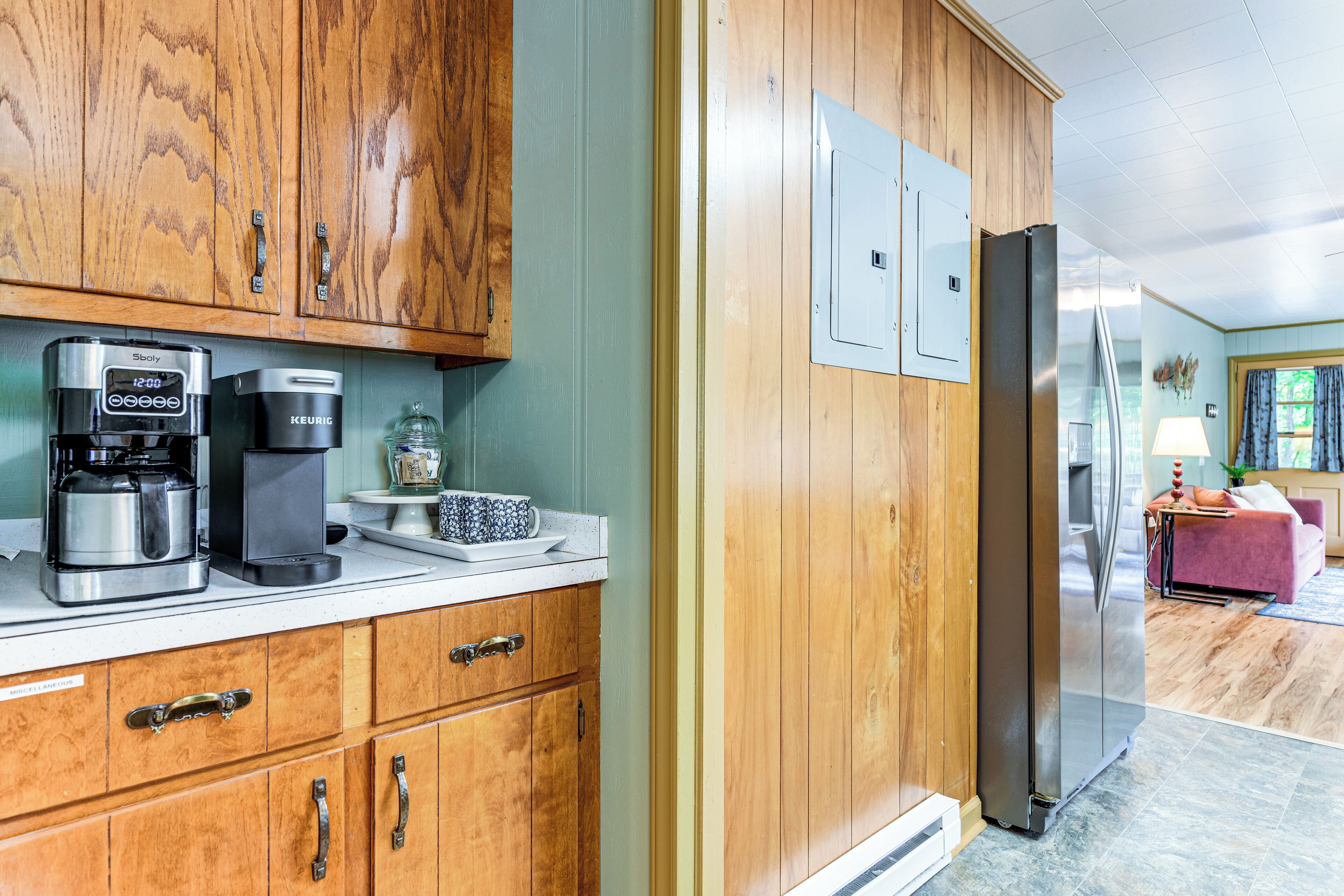 Cucina con pensili in legno, frigorifero in acciaio inossidabile e macchina da caffè.