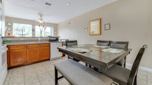 Une cuisine avec des meubles de rangement en bois, une table à manger avec des chaises et un banc.