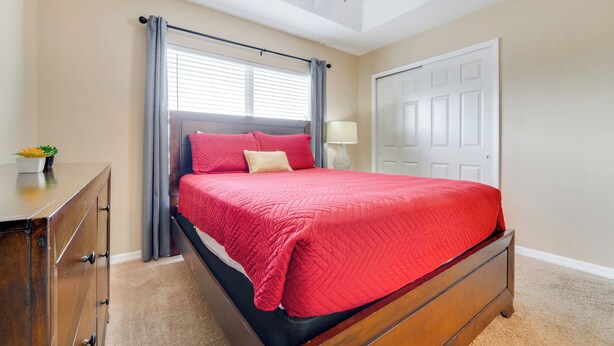 Une chambre à coucher avec un lit, une commode, un ventilateur de plafond et une porte.