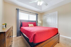 Ein Schlafzimmer mit einem Bett, einem Schminktisch, einem Deckenventilator und einer Tür.