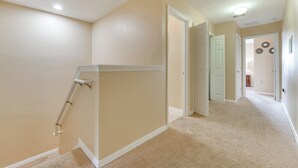 Un couloir aux murs et au tapis de couleur beige, qui mène à une porte.