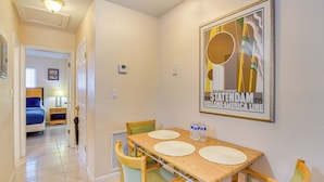 Habitación de hotel con comedor que incluye una mesa de madera, cuatro sillas y una obra de arte colgada en la pared.