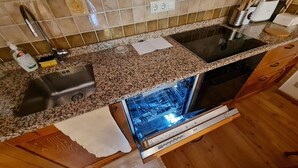 A kitchen with a granite countertop, stainless steel sink, and a dishwasher.