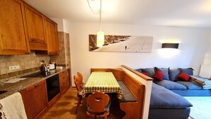 A kitchen with wooden cabinets, a dining table with chairs, and a blue sofa with cushions.