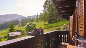 Una terraza de madera con vistas a un valle verde y montañas.