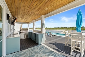 A covered outdoor area with a kitchen, poolside seating, and a view of the ocean. - The Sea Suite: Lovely Sugar Sands Home- Priv. Pool, Sleeps 18, Game & Movie Room (Mexico Beach)
