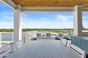 Une terrasse extérieure couverte avec une piscine, des chaises longues et une vue sur l’océan.