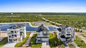 Un quartier résidentiel comprenant trois maisons blanches, une grande étendue d’eau et un parking.
