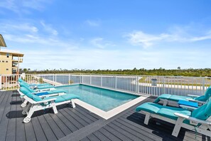 Une piscine sur le toit, dotée de chaises longues et offrant une vue sur l’océan.