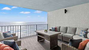 Een balkon met rieten meubilair, een tafel en uitzicht op zee.