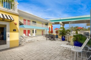 Une cour d’hôtel avec des sièges en plein air, un espace abrité et une vue sur le ciel.