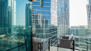 A modern balcony with two chairs and a glass table, offering a city view. - Cozy Luxury 1BR Apt in Business Bay (Dubai)