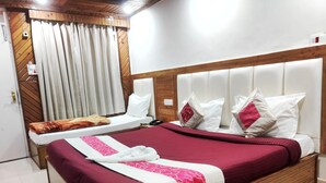A double bed with a wooden headboard, a red and white bedspread, and multiple pillows. - Hotel Hans (Shimla)