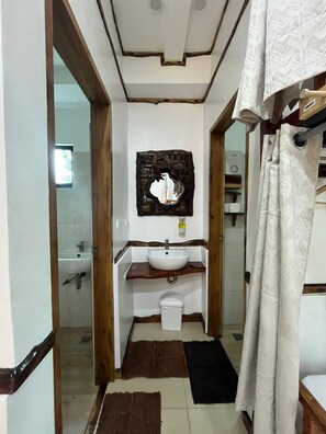 A bathroom with a white sink, wooden vanity, and a mirror with a decorative frame. - The Hat Trick Hostel (Moalboal)